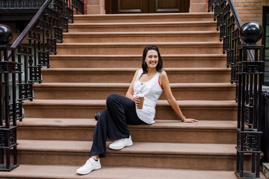 Sarah Gilliam sitting on brownstone steps with a coffee