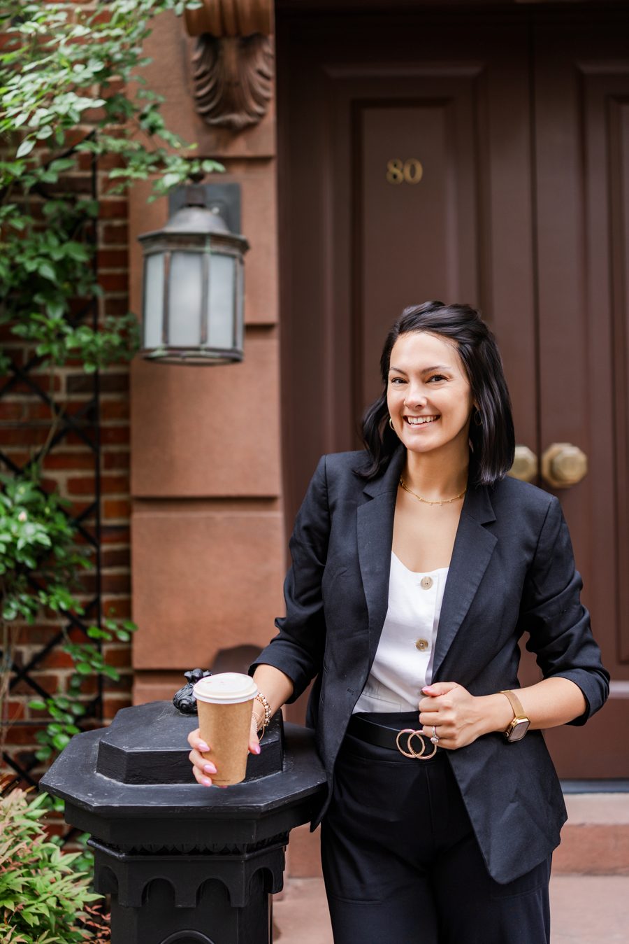 Sarah Gilliam holding a coffee on a brownstone doorstep in New York